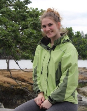 A smiling young woman in a green jacket