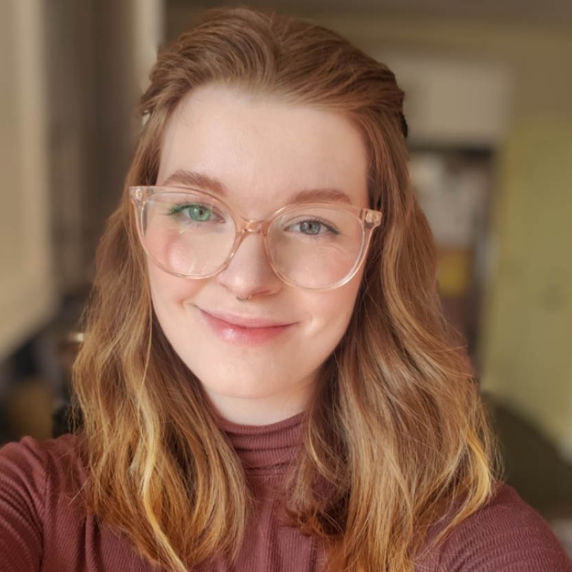 Smiling young woman with long blond hair and glasses. 